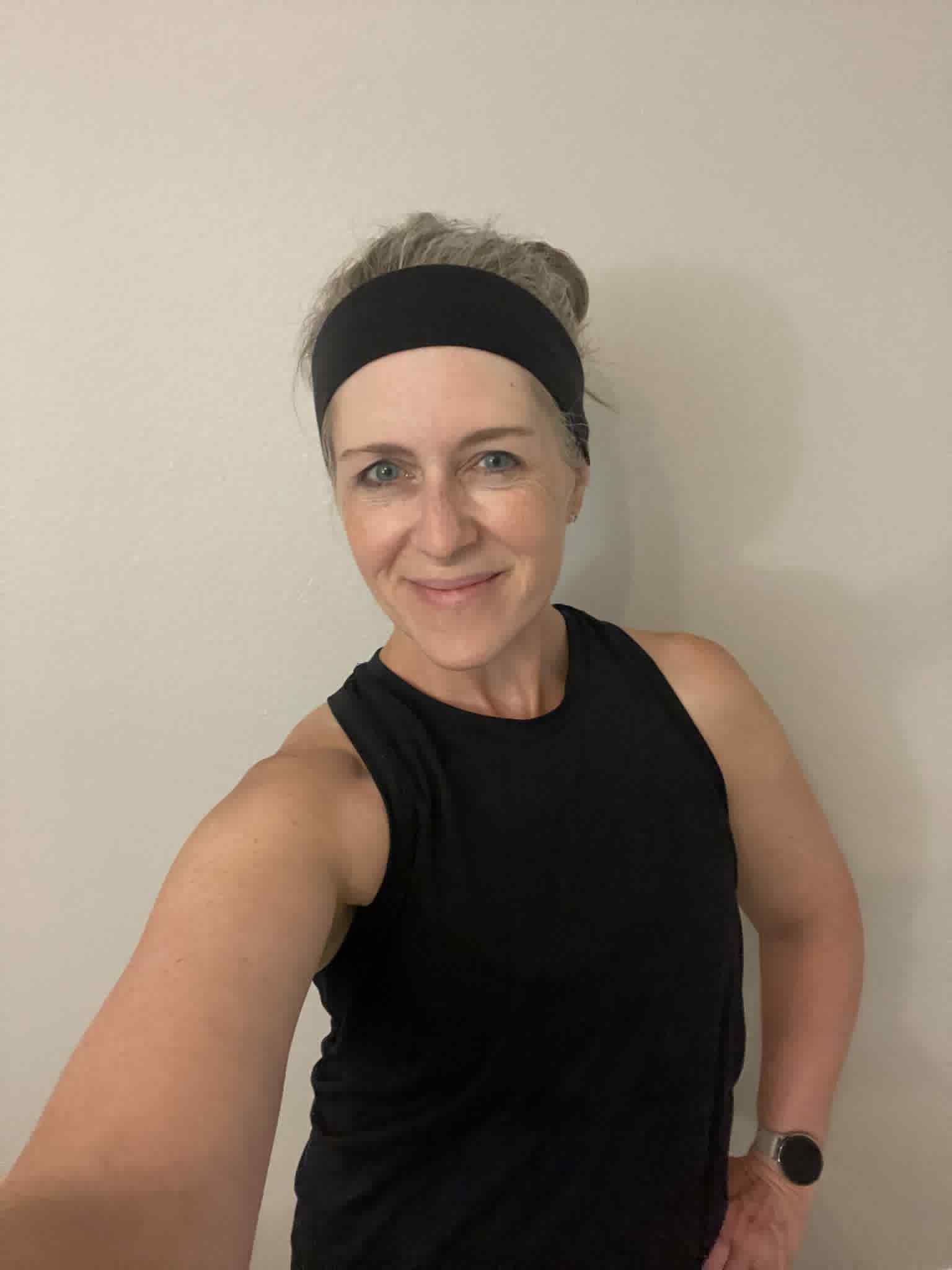 Woman wearing a black sleeveless top and headband against a plain background